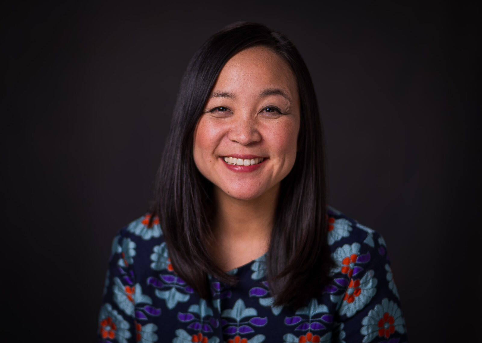 Executive portrait of a smiling woman against a dark background
