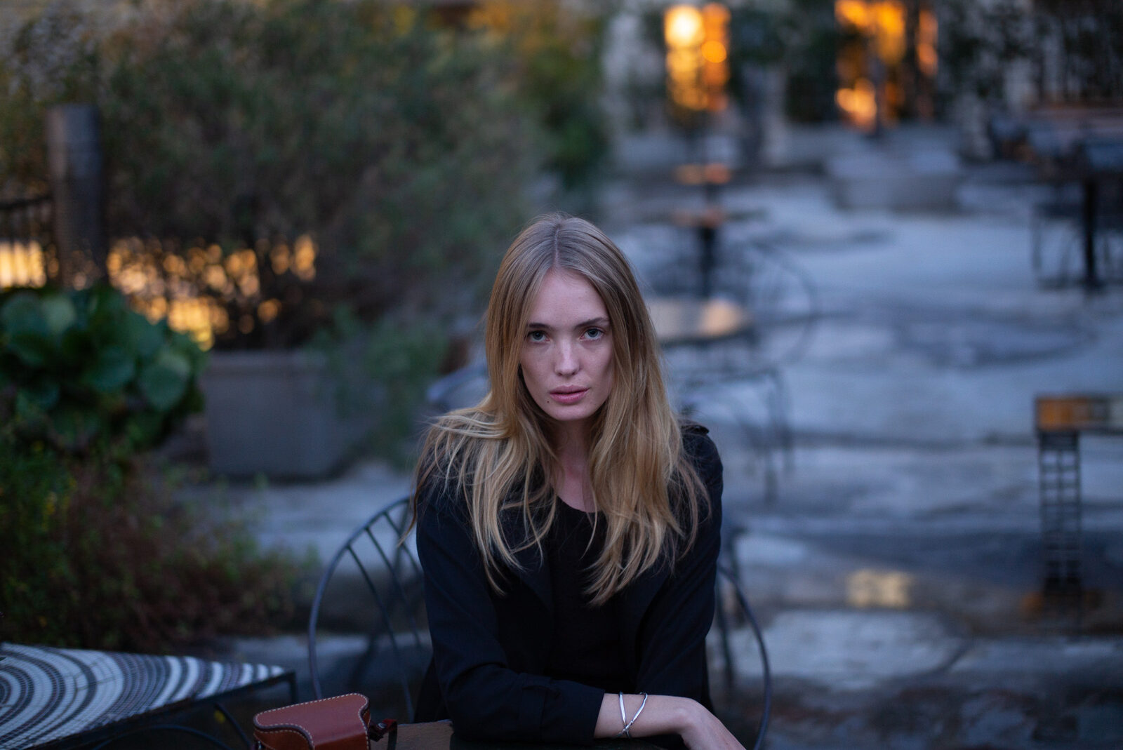Portrait of a woman seated at a cafe table at dusk